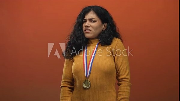 Young woman wearing a winner medal pushing hands forward, palms out gesture in an orange studio setting with rust tone; disgust refusal.