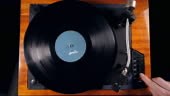 Person turns on a musical player, placing a needle on a vinyl record....