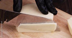 cut hard cheese with holes cut into thick pieces on a cutting board, large pieces of cheese for pizza and snacks