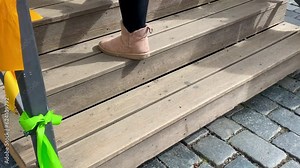 Women's legs in warm boots and felt boots climbing the stairs in slow motion.