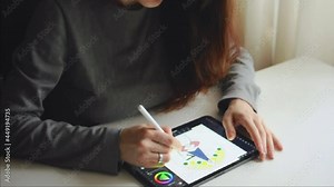 Female is drawing a picture using stylus on touchpad. ultimately grey clothes