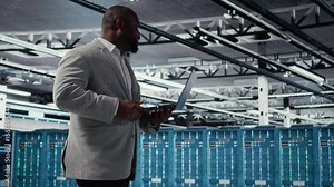 Admin walking in data center industrial platform analyzing infrastructure performance outputs on laptop. Server farm worker doing job tasks, finetuning mainframes configurations, camera A