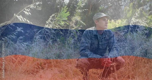 Military male in camo uniform sitting in grass, tricolor overlay revealing him while scanning area