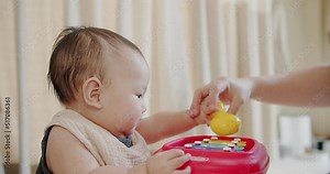 happy little cute Asian baby child playing hitting colorful instrument music toy with family mother and smiling while sitting and having fun in living room at home, toddler musician learn melody