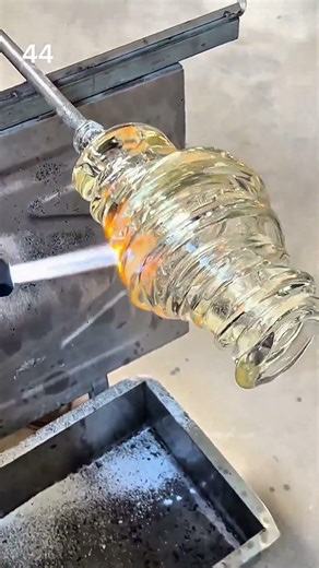 Heating and shaping molten glass on a rotating rod using a blowtorch to form a decorative piece