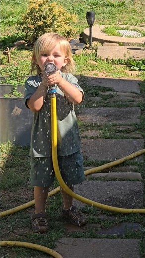 Toddler learning about a water hose #farmlife #Summertimefun #gardeningwithkids