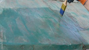 Worker applying rust converter to old metal roof plate, closeup of hand and brush tool