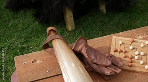 Medieval board game with wooden pieces on a rustic table, next to a horn and leather gloves, evoking historical viking leisure