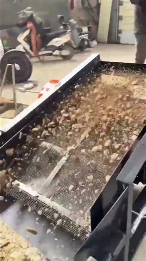 Sifting loose soil from rocks and debris using a motorized vibrating screen to produce fine dirt