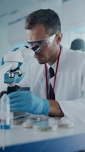 Vertical Video. Medical Development Laboratory: Male Scientist Looking Under Microscope, Analyzing Sample. Specialists Working on Medicine, Biotechnology Research in Advanced Lab. Side View