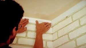 Craftsman mounting a white ceiling molding indoors