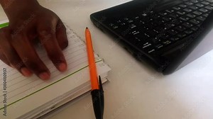 Black woman's hand anxiously tapping her fingers on a notebook footage, video clip. Pen on notepad. Laptop in background. Work stress concept. Thinking, wondering, worried. Wondering. Stressed. Africa