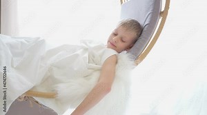 Cupid with white wings and an arrow with a red heart. Valentine's day child dressed as an angel with wings. 4k video in a white studio. Congratulations on Valentines Day. Boy waving his heart