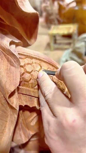 carving detailed hexagonal patterns into a wooden statue with a small metal tool