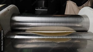 Dough sheeter. A close-up video of the rolled out viennoiserie dough. Laminated dough on the dough sheeter machine. Croissant production concept.