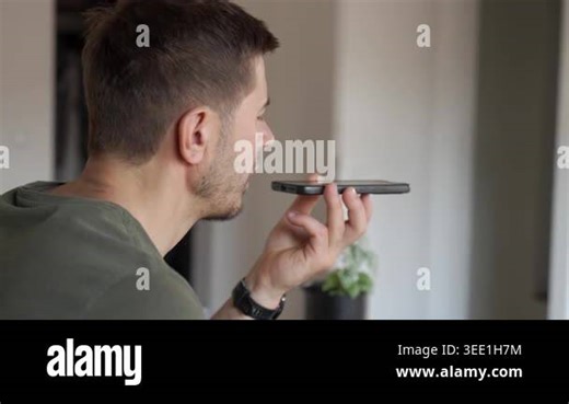 Side view of man recording voice message on smartphone while writing in notebook at desk by window. Concept of mobile communication, speech input, note taking and remote work Stock Video Footage - Alamy
