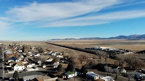 Aerial-Residential area of the small rural town of Milford, Utah in the Great Basin desert of western United States to railroad cars on siding in the train yard Stock Video