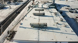 Workers installing new industrial HVAC rooftop unit onto office building, aerial