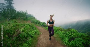 Gorgeous fitness woman runs along beautiful mountain trail