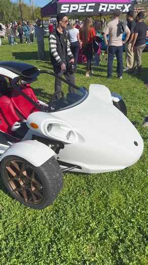 This is a Campagna T-Rex, a two-seat, three-wheeled motor vehicle. It is powered by a motorcycle engine, with current models using a 1.4 L inline-four from Kawasaki. It is classified as an autocycle and can be driven without a motorcycle endorsement in some places, such as Arizona. The vehicle has an open cockpit, no doors, and sits very low to the ground. It has a sequential manual transmission operated by a hand lever, similar to a motorcycle's. 0-60 in 3.9s. It weighs about 1098lbs. Pricing s