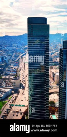 Tall contemporary blue glass building situated next to a busy multi-lane freeway with heavy traffic and city background. City skyline near highway. San Francisco. Vertical video Stock Video Footage - Alamy