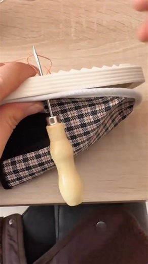 repairing a patterned fabric shoe by sewing the white rubber sole using a manual metal awl tool