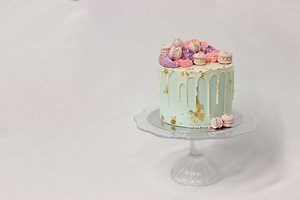 INSIGHT Stellas Cake Rich chocolate cake layered with dark chocolate ganache and homemade salted caramel, covered with white chocolate ganache and finished with mini Macarons, colourful buttercream and gold leaf | Magnolia Kitchen