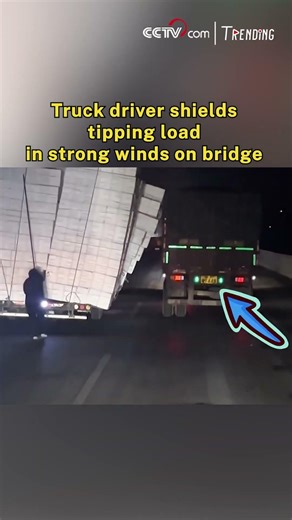 Truck driver shields tipping load in strong winds on bridge
