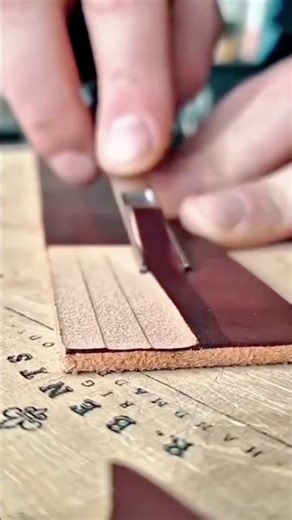 scraping the brown leather material using a sharp metal chisel tool on the wood board indoor area
