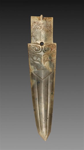 At least 3000 years old, this detailed dagger-axe (ge) is attributed to the Shang dynasty of ancient China. It is made of jade (nephrite) and features a symmetrically carved, pointed, and slightly curved blade emerging from the mouth of a taotie animal mask, with curved horns in relief and fine threadlike detailing on the eyes, snout, and upper jaw. It measures 4.4 cm (1 3/4 in) in length. This artifact is now housed at the Cleveland Museum of Art in Cleveland, Ohio, United States. It was purcha