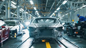 Workers assemble vehicles on an automated production line, showcasing the modern manufacturing process in an industrial facility