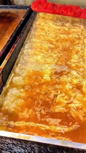 Blue-gloved hands lifting thin sheet from paper pulp