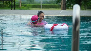 Little girl plays in the outdoor swimming pool of tropical resort during family summer vacation. Kids learning to swim. Healthy Summer Activities for Kids.