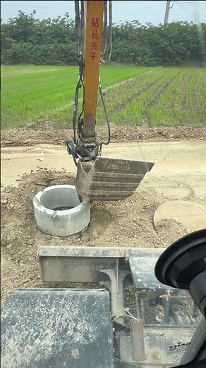 Excavator Installing a Concrete Manhole Cover with a Hydraulic Clamp