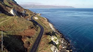 Northern Ireland, UK, Atlantic coast with cliffs. Antrim Coast Road a.k.a. Causeway Coastal Route. One of the most scenic coastal roads in Europe. Aerial 4K video. Winter, sunrise light