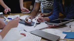 Close-up shot of hands of multiethnic male and female designers discussing colors, material samples, using tablet and writing in notepad while working in team on creative project