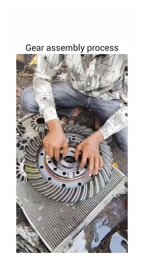 @gearheadgiggle on Instagram: "The video shows a detailed mechanical assembly process involving a large circular gear with a central hole and multiple bolt holes. A person wearing a patterned shirt and jeans works methodically on the component, beginning by placing a smaller gear-like part onto the larger gear, aligning it precisely. They then insert a cylindrical object into the center of the smaller gear, ensuring a snug fit. Next, they pour a purple liquid—likely a lubricant—into the central 
