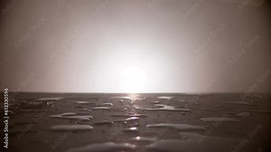 slow motion of a tomato rolling from right to left on a wet table