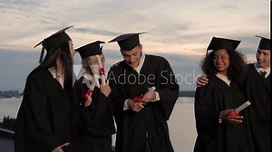 Group of happy graduates walking to graduation ceremony in the evening.