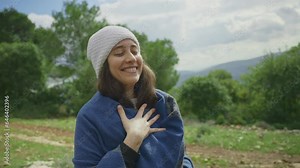 Young hippie woman feeling joyful and happy in nature hugging herself and smiles. Pure happiness female bohemian is grateful and thankful surrounded by green forest and fresh air. Breathing deep