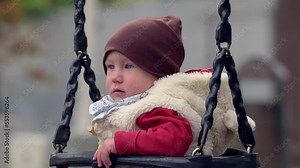 childhood, park - serious child swinging on the swing at the playground