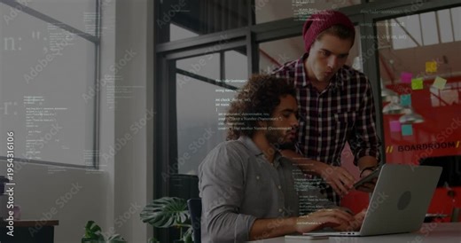 Standing peer leaning and pointing at laptop seated man pausing and checking tablet for tech design