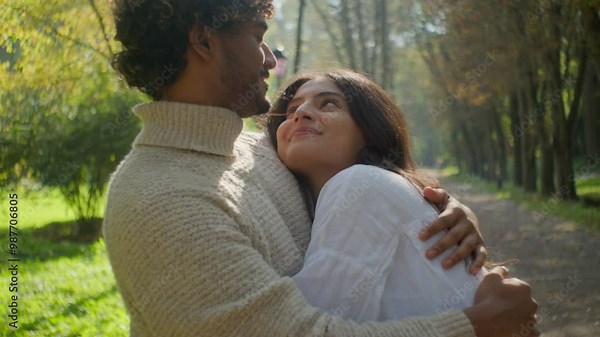 Happy multiethnic loving romantic couple family Arabian Indian man Hispanic woman smile cuddle touching. Male boyfriend female girlfriend hug relaxing on date together embrace in nature park outdoors