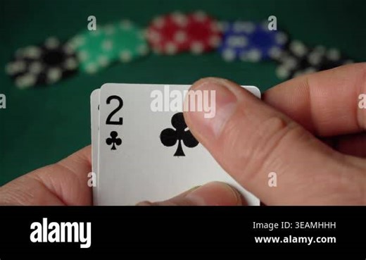 Player holds two playing cards, both showing two of clubs and two of spades, while colorful poker chips are arranged in the background on a green felt table surface Stock Video Footage - Alamy