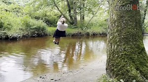 Woman fails to cap off rope swing fun with proper landing, resulting in a splash in muddy water