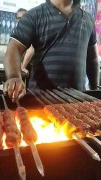 Kebabs and meat skewered over charcoal in large quantity.
