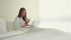 Download Woman typing on laptop in bed for free