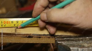 Carpenter using tape measure and pencil on wood