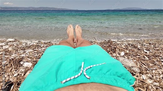 Man sunbathing on a rocky sea ocean beach.