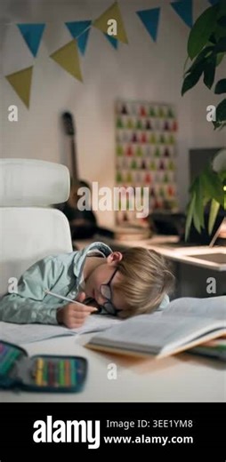 A little boy wearing glasses is doing his homework at a table in a home setting. He is sitting in his bright room at white table, where his textbooks, copybook and an open pencil case filled with Stock Video Footage - Alamy